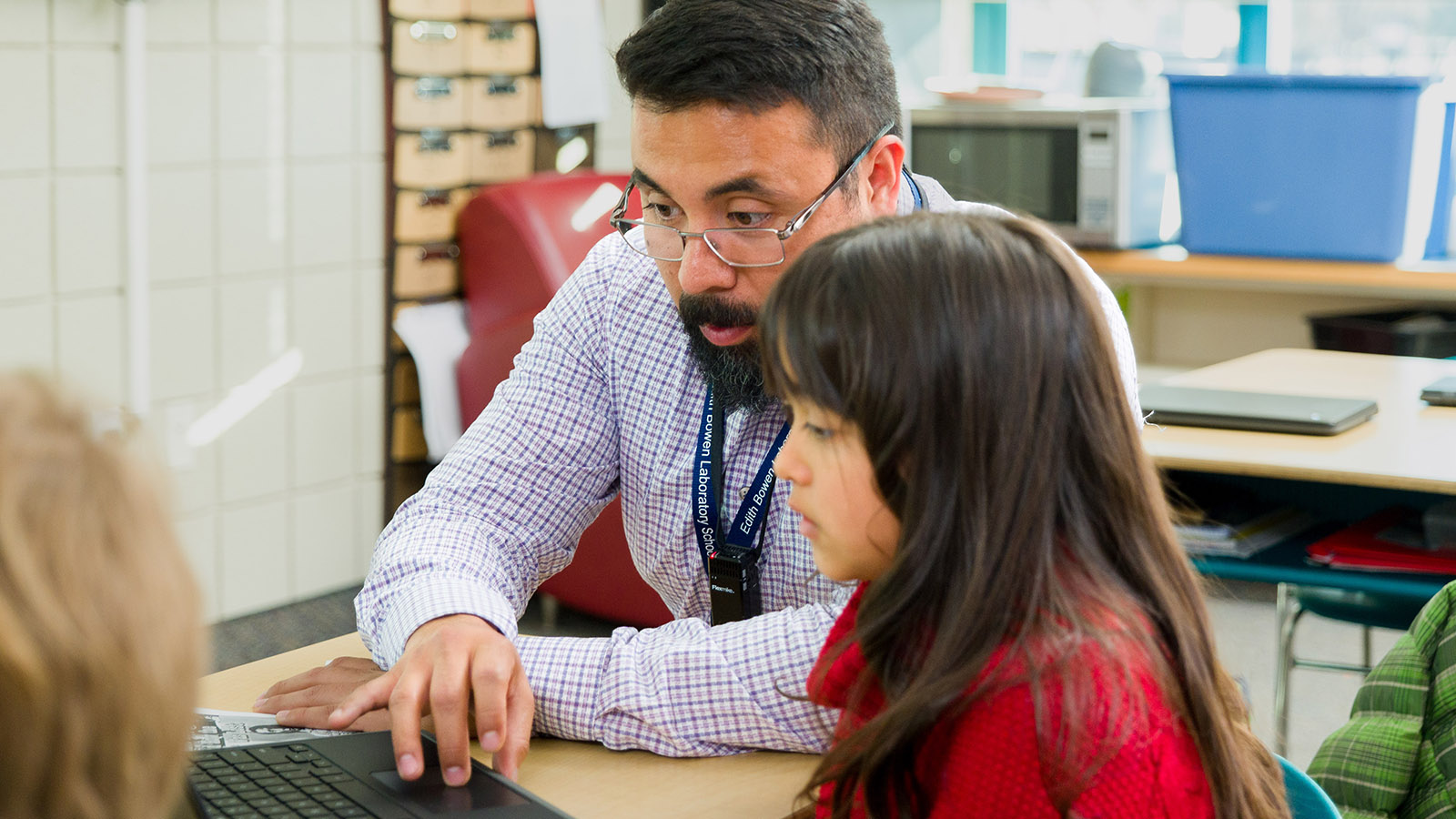 a teacher helps a student at a computer
