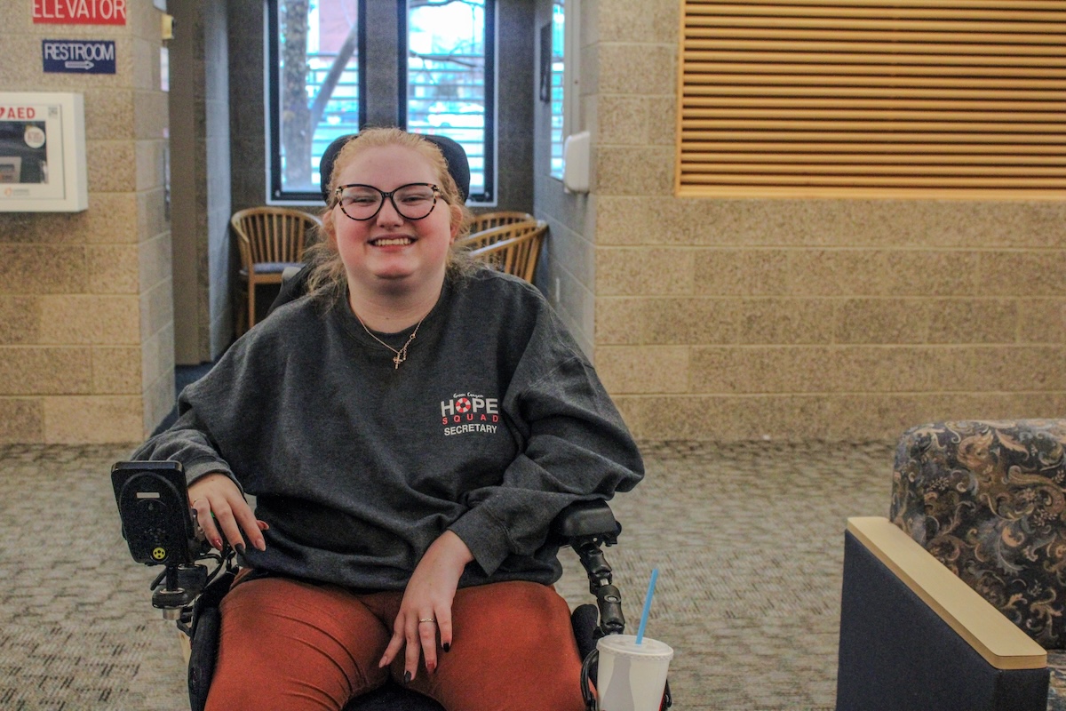 A young woman sits in a wheelchair smiling.