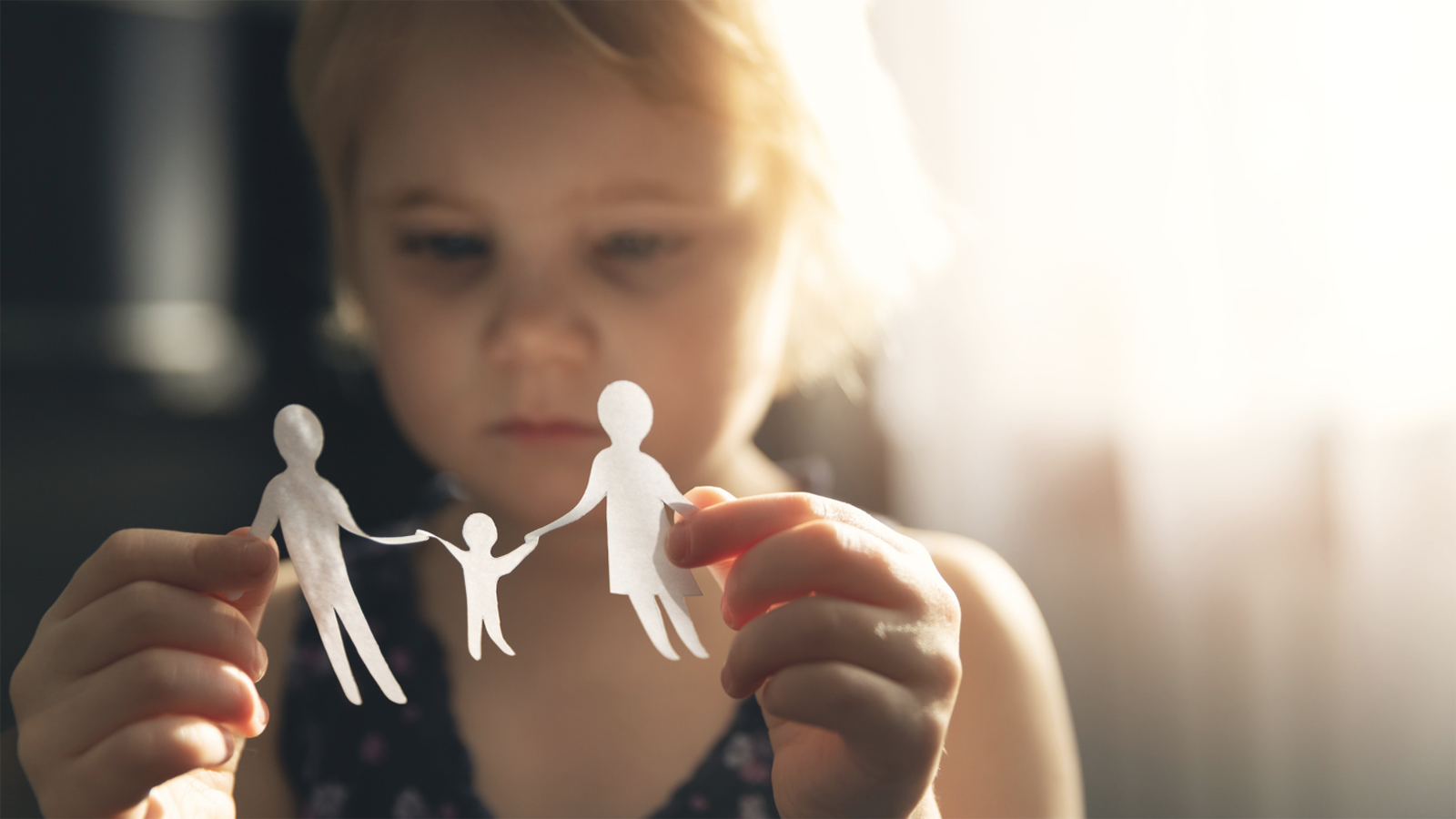 illustration of a little girl holding up paper silhuettes of a family