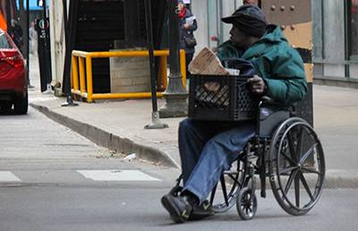 A man in a wheelchair with a crate of belongings on his lap