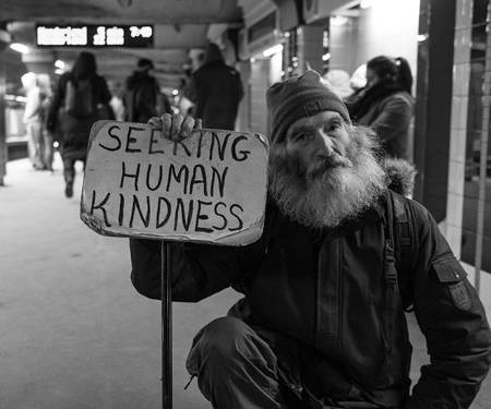 homeless man holds up a sign: "Seeking human kindnes"