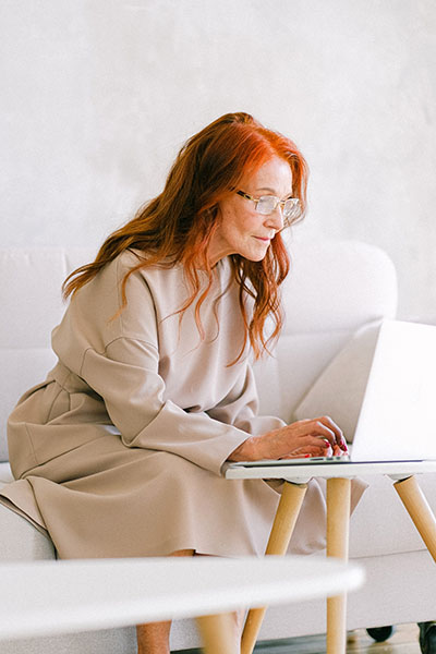 a senior woman types at a laptop