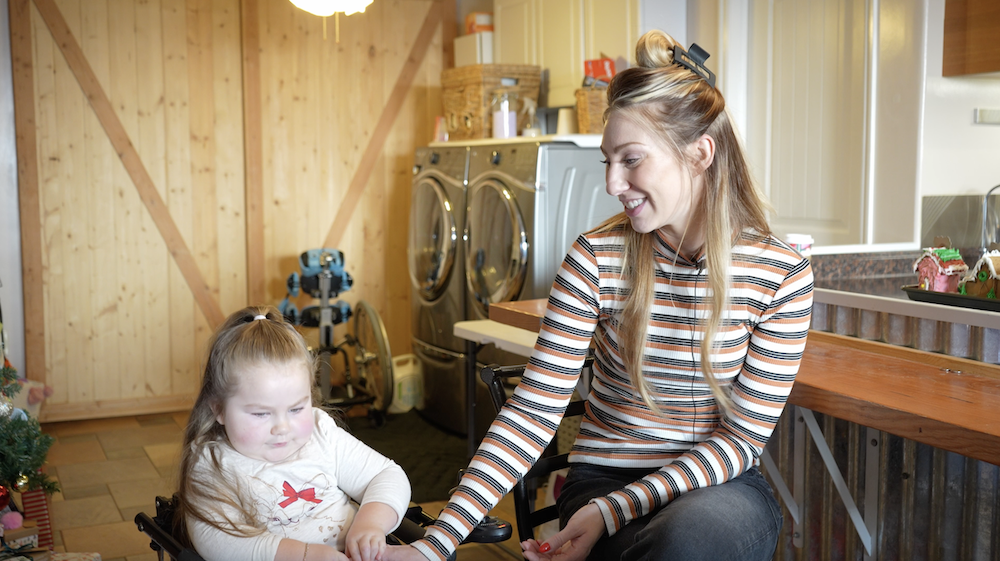 A woman sits next to her daughter who is in a wheelchair.