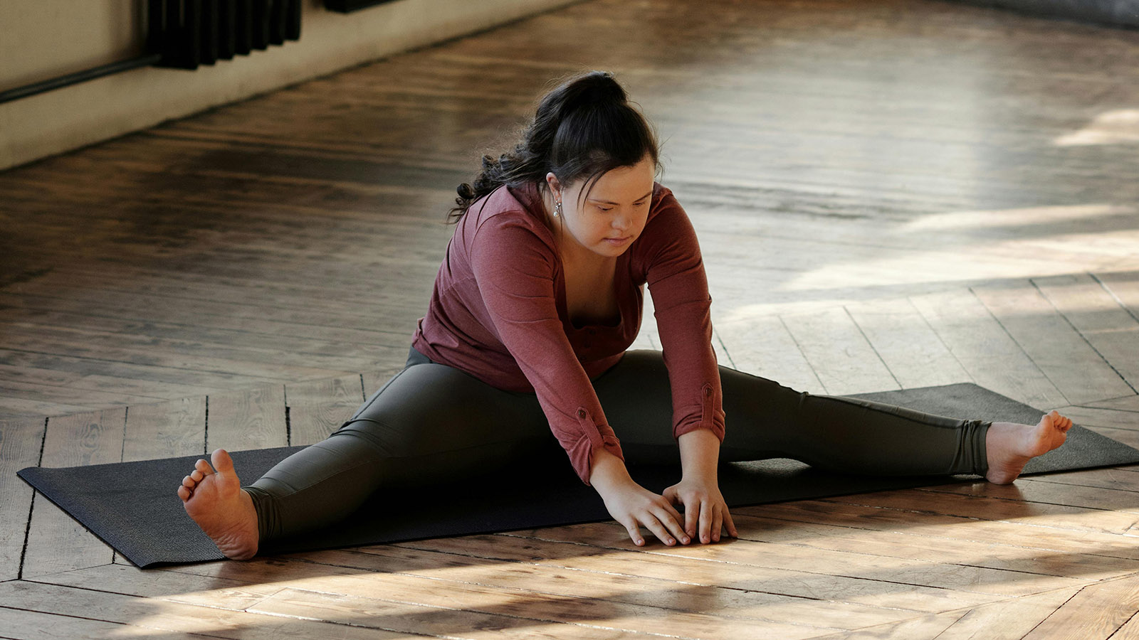 a woman with Down syndrome stretches on a yoga mat