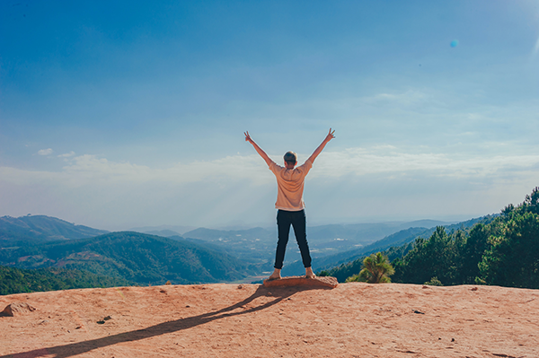 Person standing on a mountain with arms raised high in the air