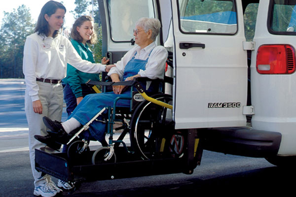 an elderly woman in a wheelchair is loaded into a van