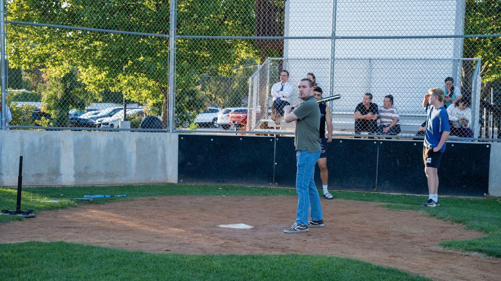An older individual is up to bat on a baseball field.