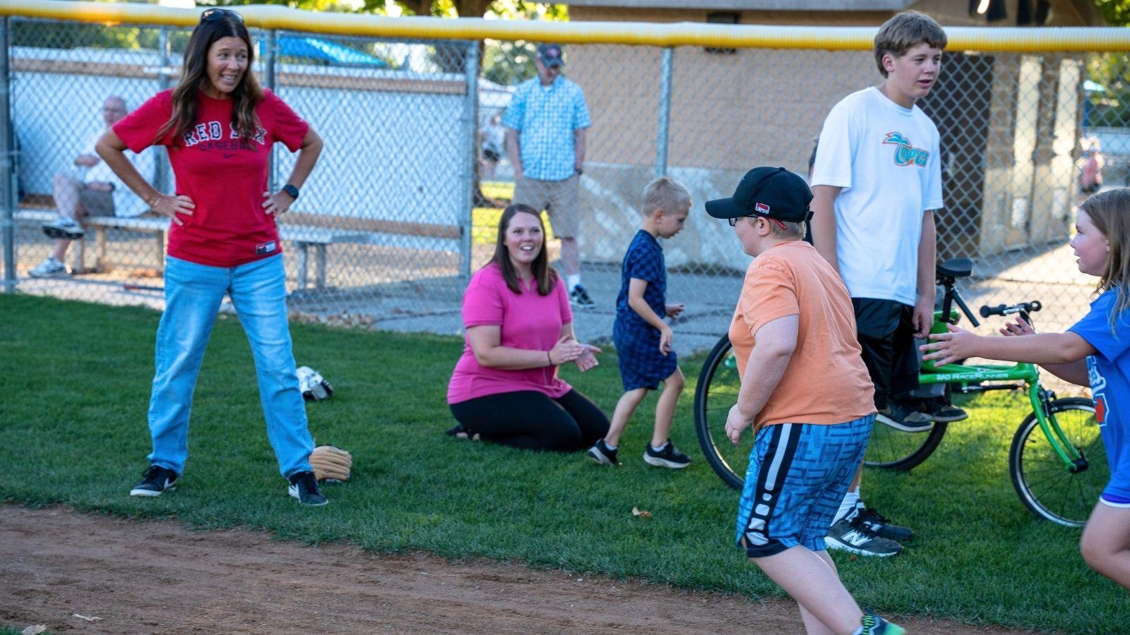 Erica Lundahl cheers on individuals running to first base on a baseball field.