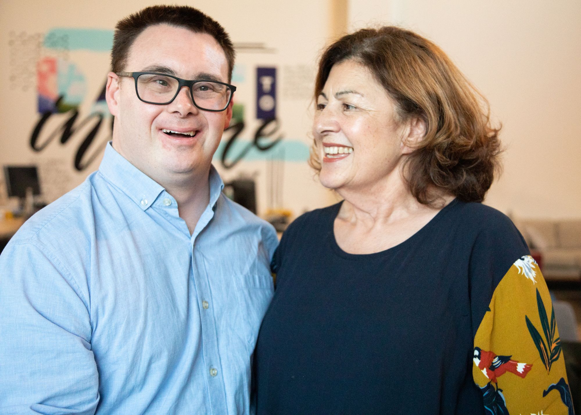 A man with a disability and an older woman standing together smiling.